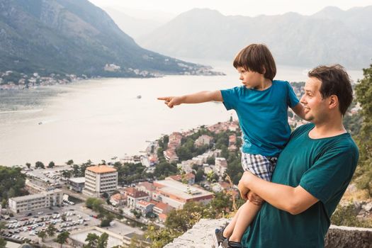 Father holding little son looking at the panoramic view of the Kotor Bay in Montenegro.