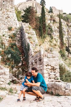 Father and son checking the photo they just took on the cell phone while climbing on the Kotor Castle in Montenegro. Illyrian Fort