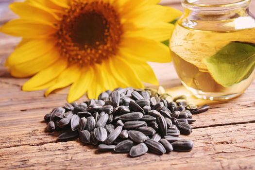 Sunflower seeds and oil bottle on old wooden background. Selective focus.nature