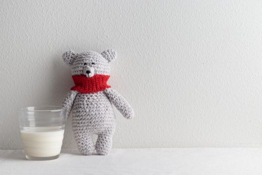 rochet knitting cute teddy bear with a glass of milk on a white table