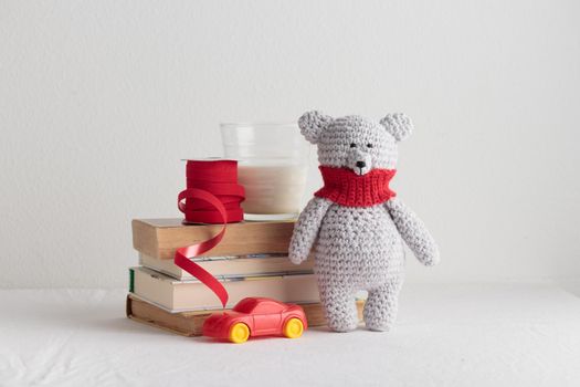 Crochet knitting cute teddy bear with books and a toy on a white table