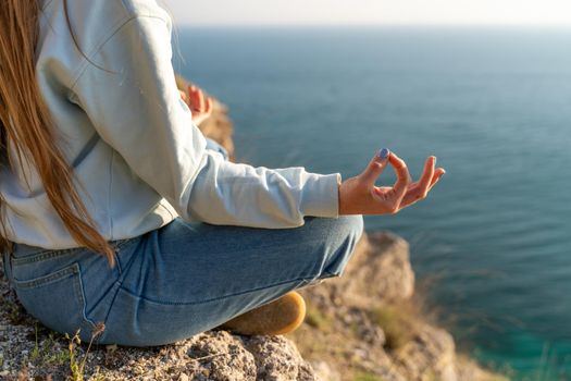 yoga, gesture and healthy lifestyle concept - hand of meditating yogi woman showing gyan mudra over sea sunset background.