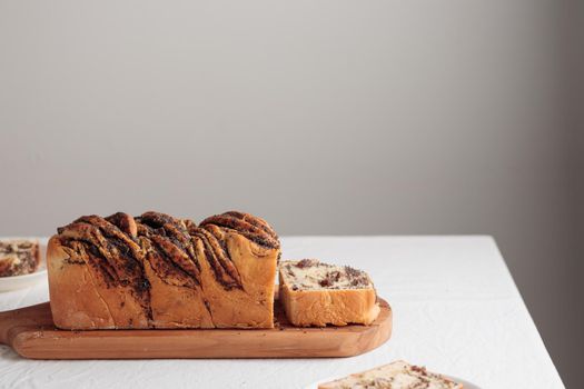 Sweet swirl homemade bread with poppy seeds on a white table