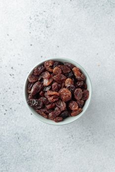 Bowl with raisins on concrete background top view