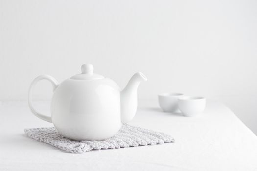 White teapot on a table on a white background