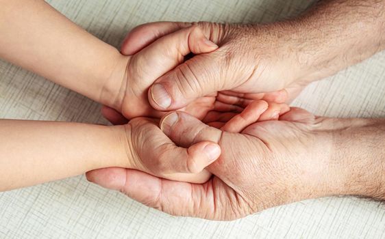 old man holding child's hands. selective focus people