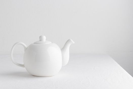 White teapot on a table on a white background