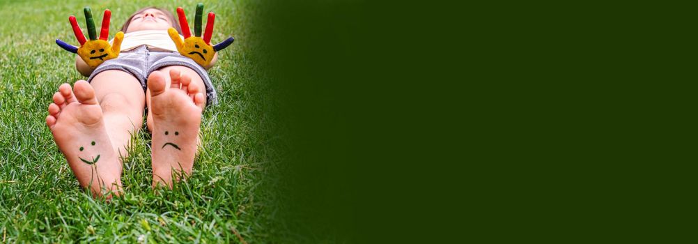 Baby feet with paint pattern are smiling and sad on the green grass. Selective focus. nature.