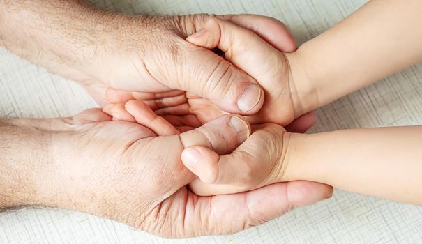 old man holding child's hands. selective focus people