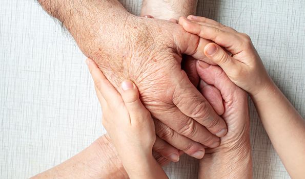 old man holding child's hands. selective focus people