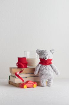 Crochet knitting cute teddy bear with books and a toy on a white table