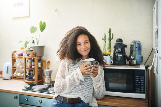 Portrait of a smiling young african woman drinking coffee early in the morning