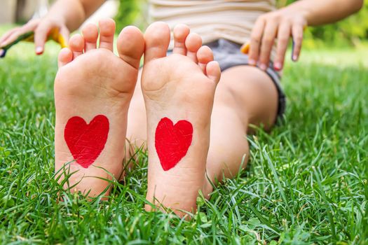 Baby legs with a pattern of a heart on the green grass. Selective focus. nature.