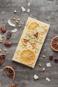 Craft chocolate with fruits and nuts on a gray background