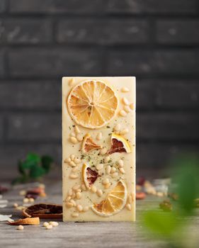 Craft chocolate with fruits and nuts on a gray background