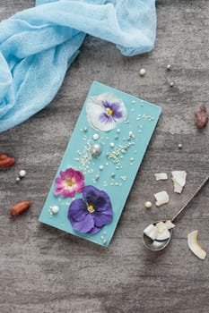 Craft chocolate with fruits and nuts on a gray background