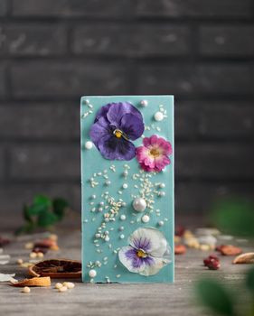 Craft chocolate with fruits and nuts on a gray background