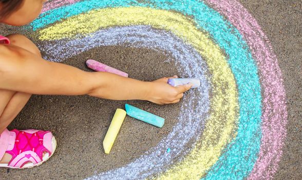 A child draws a rainbow on the asphalt. Selective focus. kid.