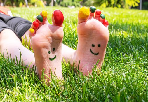 Children's feet with a pattern of paints smile on the green grass. Selective focus. nature.