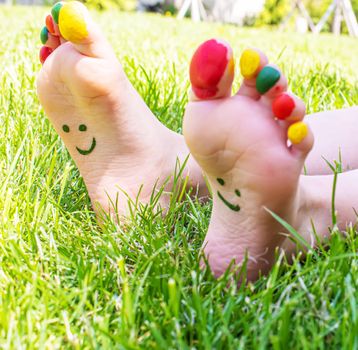 Children's feet with a pattern of paints smile on the green grass. Selective focus. nature.