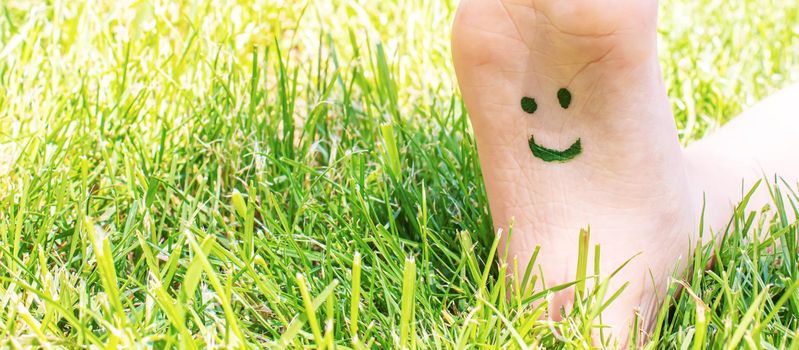 Children's feet with a pattern of paints smile on the green grass. Selective focus. nature.