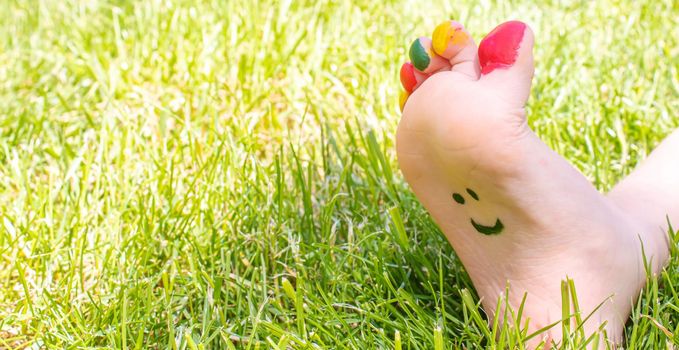 Children's feet with a pattern of paints smile on the green grass. Selective focus. nature.