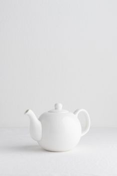 White teapot on a table on a white background
