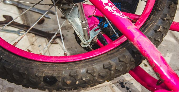 A father repairs his daughter's bike. selective focus