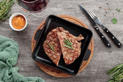 Served grilled meat steak in a metal pan on a gray table