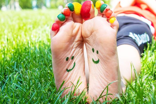 Children's feet with a pattern of paints smile on the green grass. Selective focus. nature.