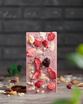 Craft chocolate with fruits and nuts on a gray background