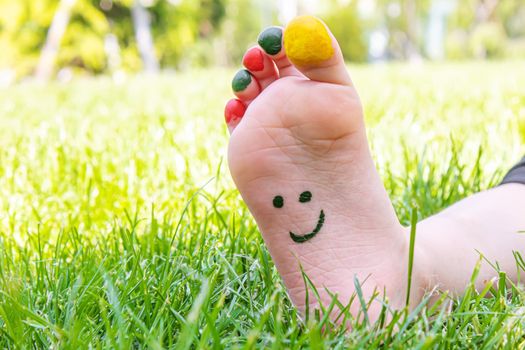 Children's feet with a pattern of paints smile on the green grass. Selective focus. nature.