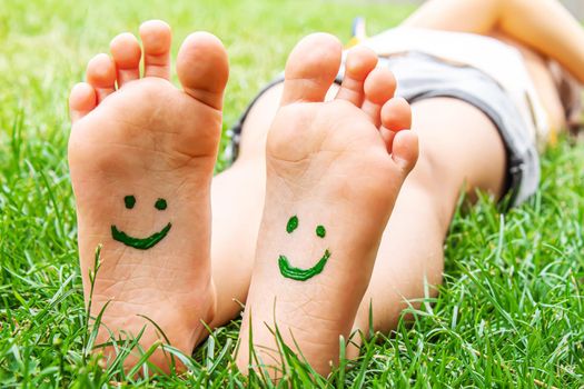 Children's feet with a pattern of paints smile on the green grass. Selective focus. nature.