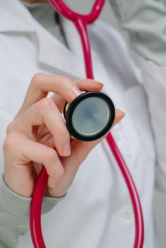 Red medical stethoscope.A doctor with a stethoscope.A doctor holding a stethoscope.The concept of healthcare.