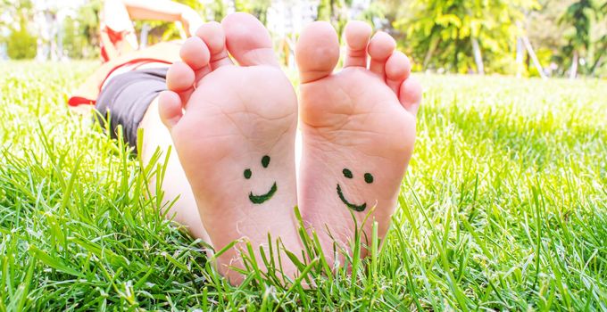 Children's feet with a pattern of paints smile on the green grass. Selective focus. nature.