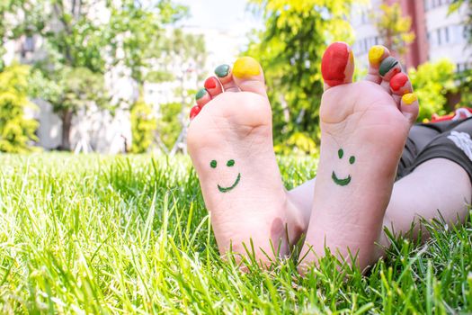 Children's feet with a pattern of paints smile on the green grass. Selective focus. nature.