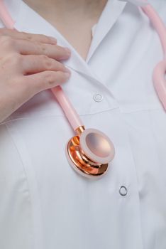 Pink medical stethoscope.A doctor with a stethoscope.A doctor holding a stethoscope.The concept of healthcare.