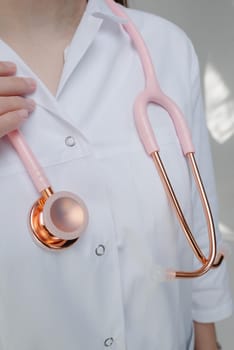 Pink medical stethoscope.A doctor with a stethoscope.A doctor holding a stethoscope.The concept of healthcare.