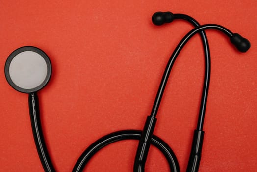 Medical stethoscope. Black medical stethoscope.The concept of healthcare.Stethoscope on a red background