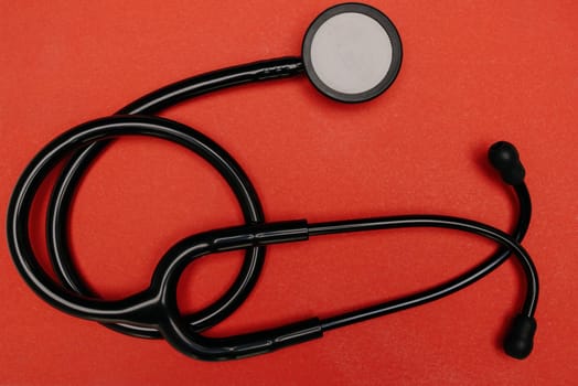 Medical stethoscope. Black medical stethoscope.The concept of healthcare.Stethoscope on a red background