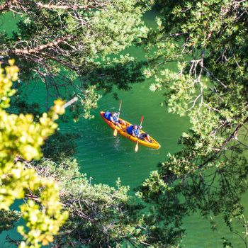 Canyon of the Tarn river, Occitanie, France - June 30 2016 - Orange canoe-kayak through the trees in the gorges du Tarn