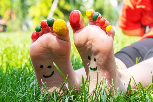 Children's feet with a pattern of paints smile on the green grass. Selective focus. nature.