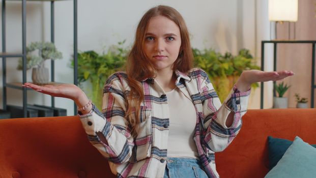What Why. Confused young woman in shirt raising hands in indignant expression, asking why, what reason of failure, demonstrating disbelief irritation by troubles, shrugs. Pretty girl indoors at home