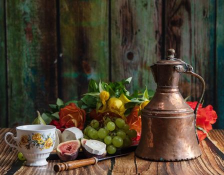 cheese plate with goat cheese, grapes and figs, copper teapot, angle view, healthy food, high-calorie breakfast. High quality photo