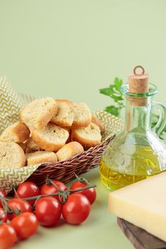 Mediterranean food: olive oil, cheese and tomatoes on a green background