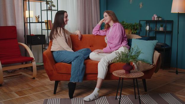 Girls friends siblings chatting talking, make support conversation consulting together. Two female women couple family secrets gossip, news rumors having great fun time together at home in living room