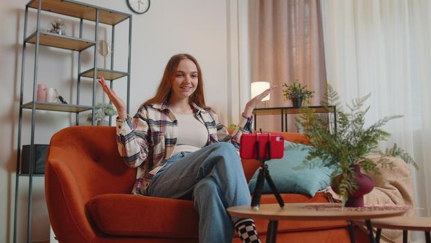 Pretty female girl blogger looks at device screen taking selfie on mobile cell phone cam, make virtual video call online on modern social media vlog application. Woman with smartphone on sofa at home