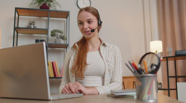 Young woman freelance wear headphone make video call tutoring, talking, teaching, looking at laptop at home office. Adult girl student study online with internet teacher learn language talk focused