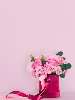 Beautiful bouquet of blooming flowers in flower box on pink background, holiday gift, luxury floral design concept