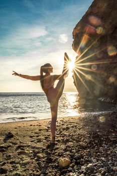 Girl gymnast is training on the beach by the sea sunset. Does twine. Photo series